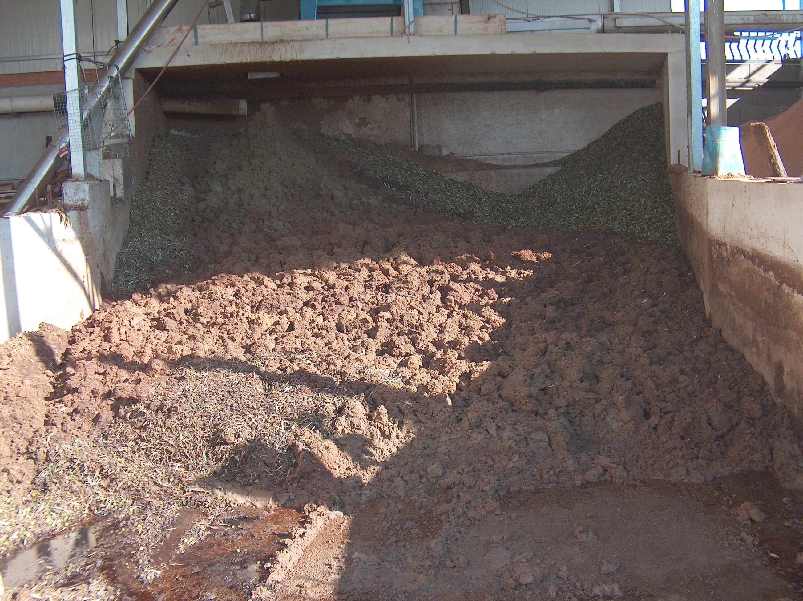 Heaps of olive pomace — the solid residue from olive pressing — in the yard of an olive mill